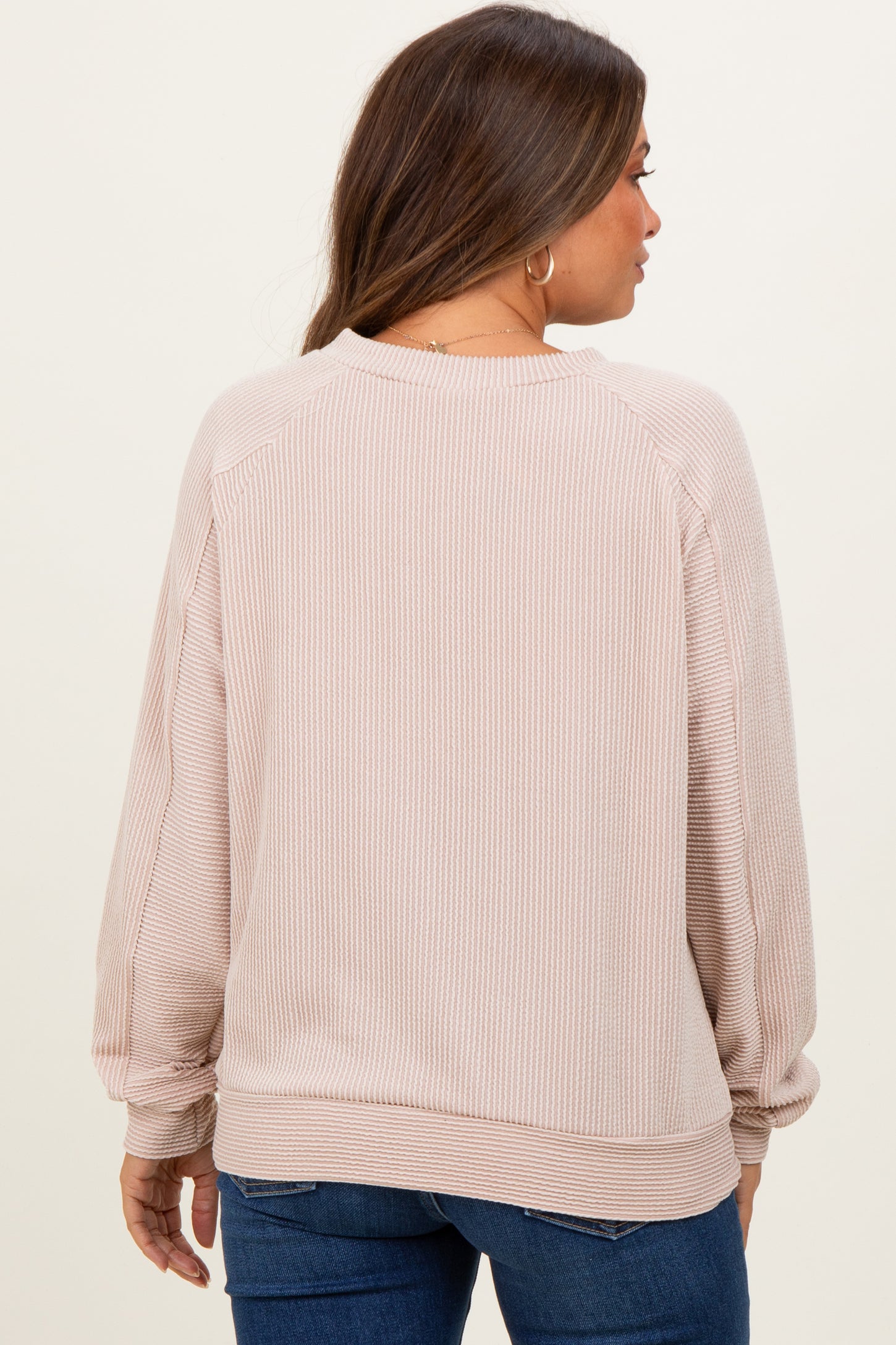 woman wearing a light pink maternity sweatshirt with ribbed texture, seen from the back