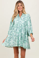 woman wearing a green floral maternity dress with a relaxed fit and balloon sleeves, showcasing a baby bump