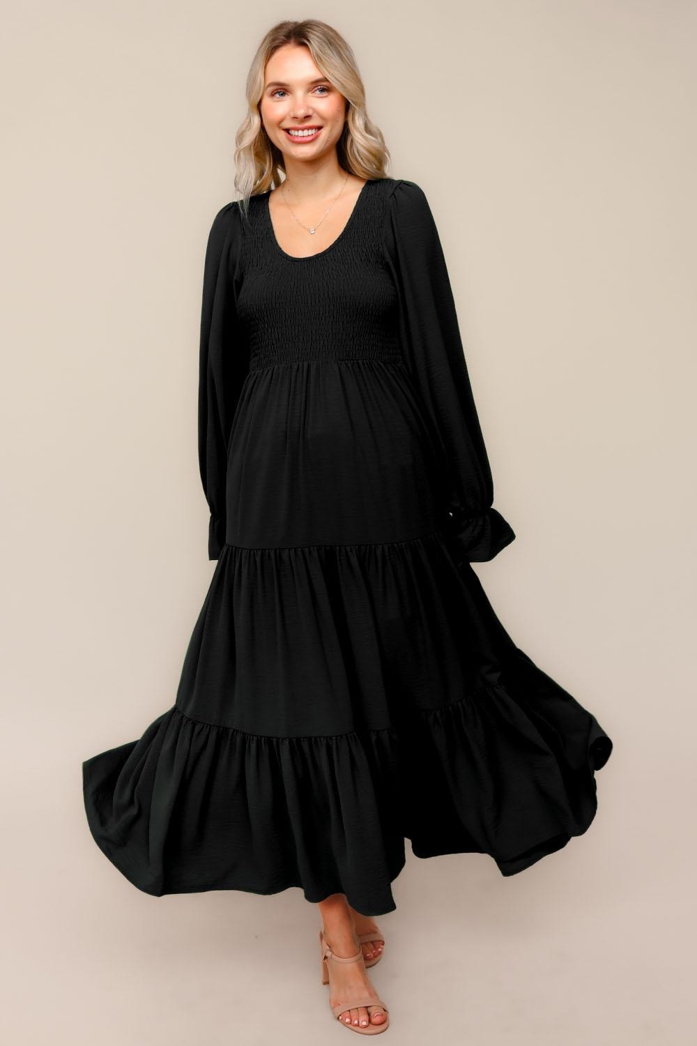 woman wearing a black long sleeve tiered maxi dress with a smocked bodice and flowy skirt