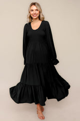 woman wearing a black long sleeve tiered maxi dress with a smocked bodice and flowy skirt
