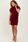 woman wearing a burgundy ribbed knit short sleeve dress with a high neckline and tan ankle boots