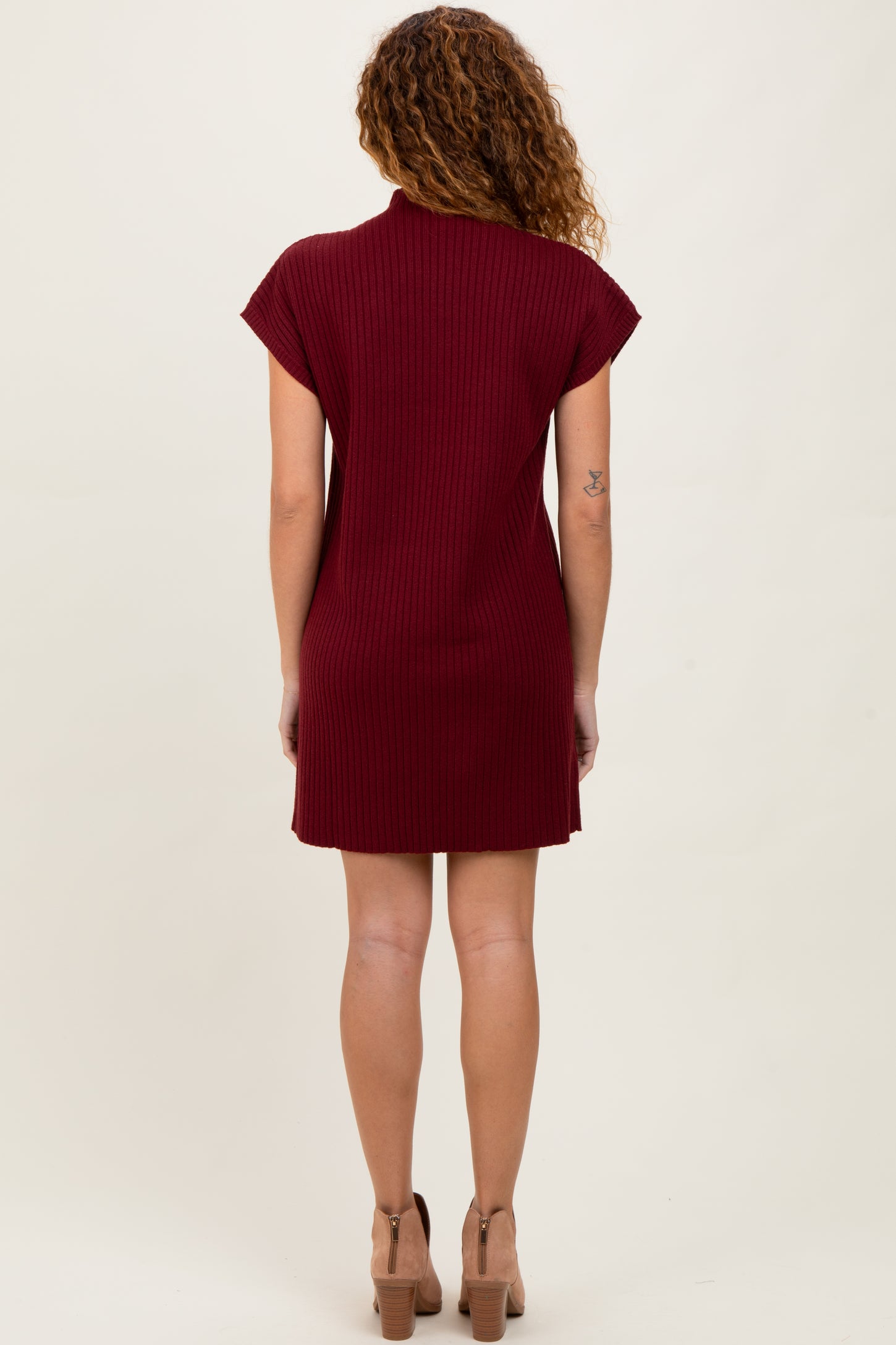 woman wearing a burgundy ribbed short sleeve dress, styled with a high neckline and a fitted silhouette