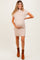 woman wearing a beige ribbed maternity dress with short sleeves and a pocket, holding her baby bump