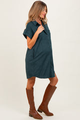 woman wearing a dark green maternity shirt dress with short sleeves and pockets, showing her baby bump