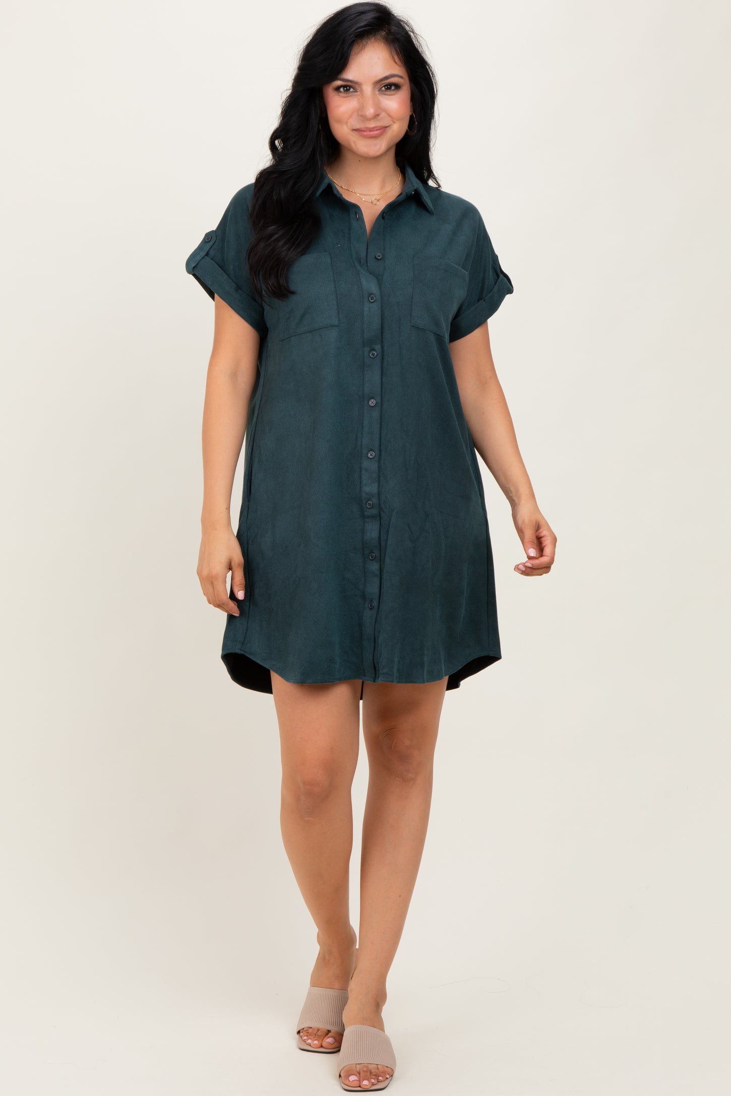 woman wearing a dark green short sleeve button-up shirt dress with two chest pockets and rolled sleeves