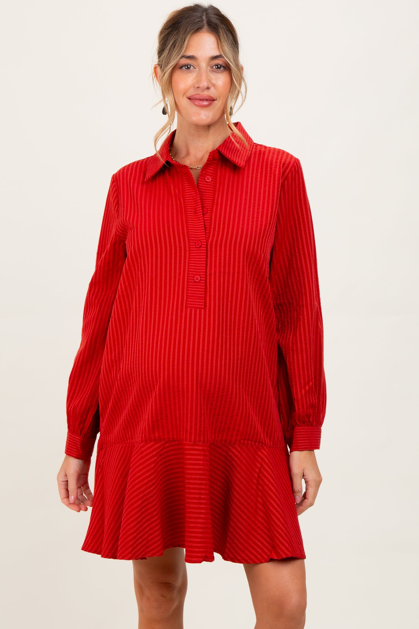 woman wearing a red striped maternity dress with a collared neckline and flared hem, showcasing her baby bump