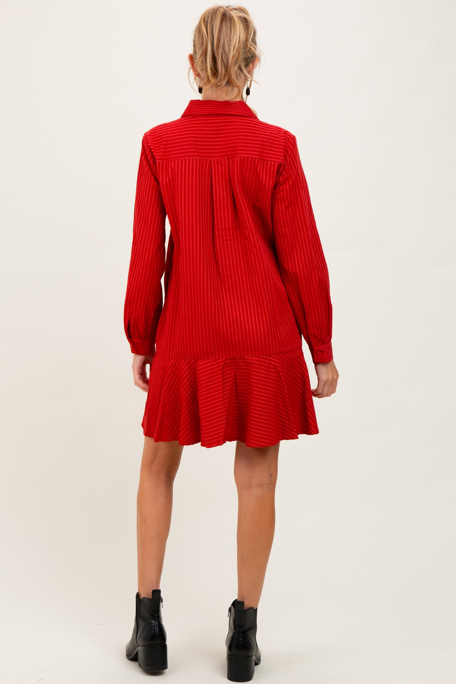 woman wearing a red striped maternity dress with a ruffled hem and long sleeves, viewed from the back