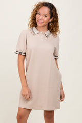 woman wearing a beige short sleeve polo dress with textured pattern and black trim details