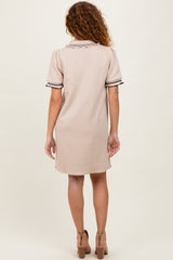 woman wearing a beige short sleeve dress with decorative ruffles and hem details, viewed from the back