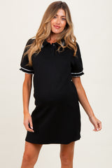woman wearing a black maternity polo dress with short sleeves and white trim, showing her baby bump