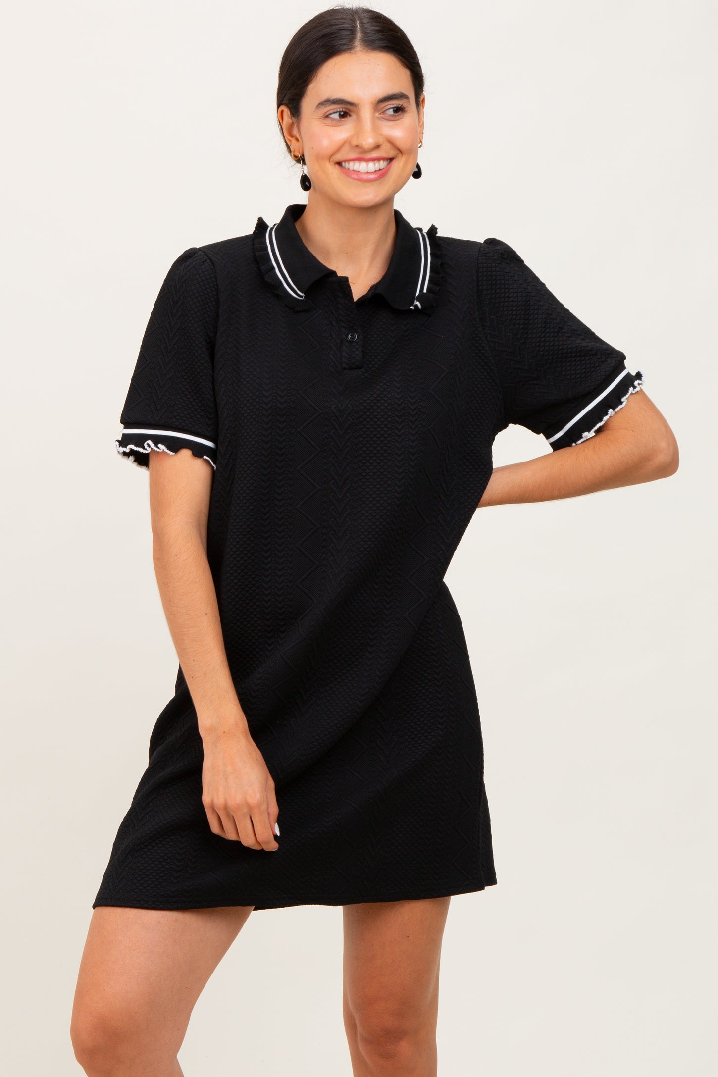 woman wearing a black polo dress with ruffled sleeves and collar detail