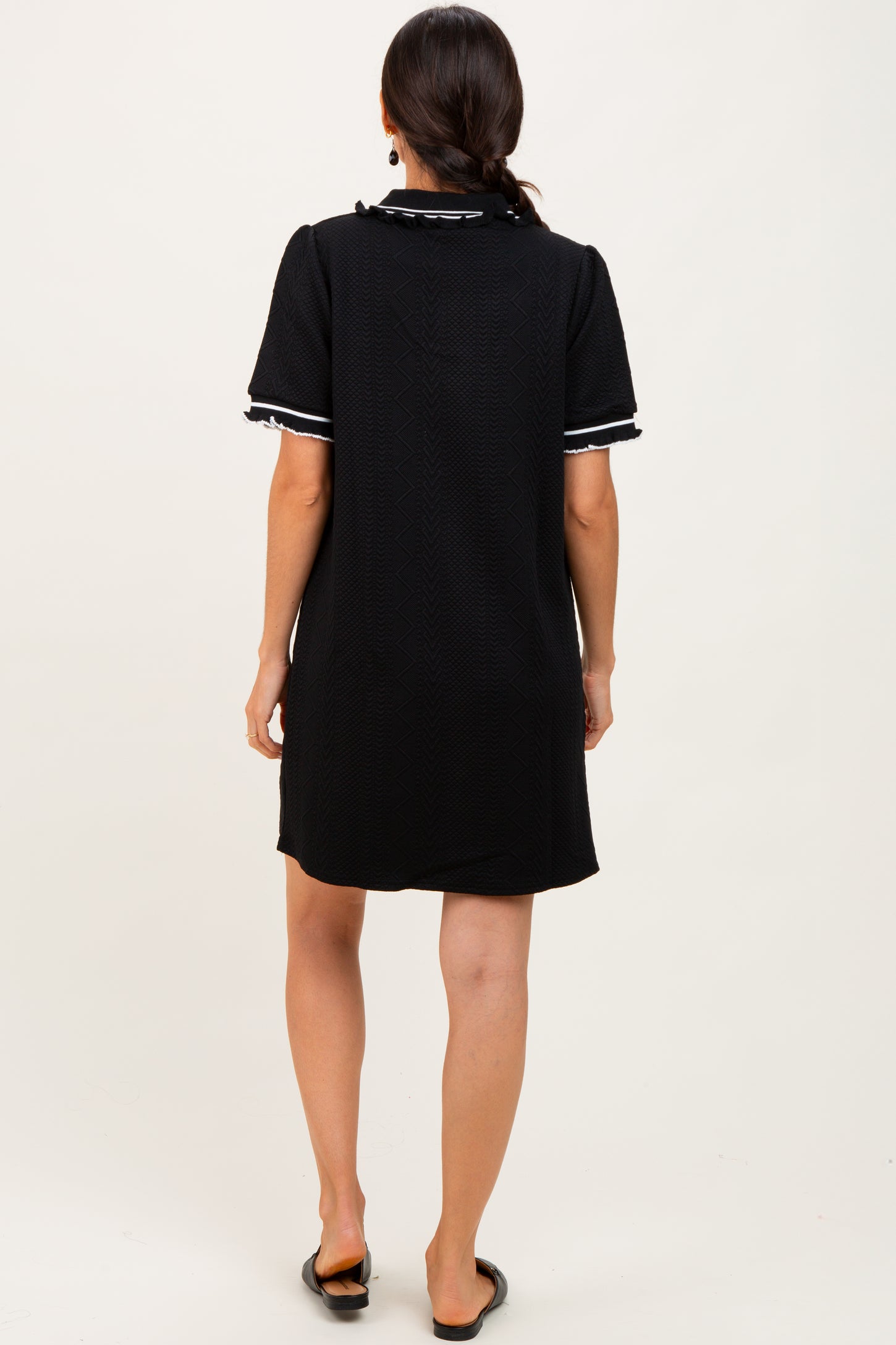 woman wearing a black short sleeve dress with white trim, viewed from the back
