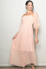 woman wearing a pale pink lace maxi dress with puffed sleeves and a square neckline
