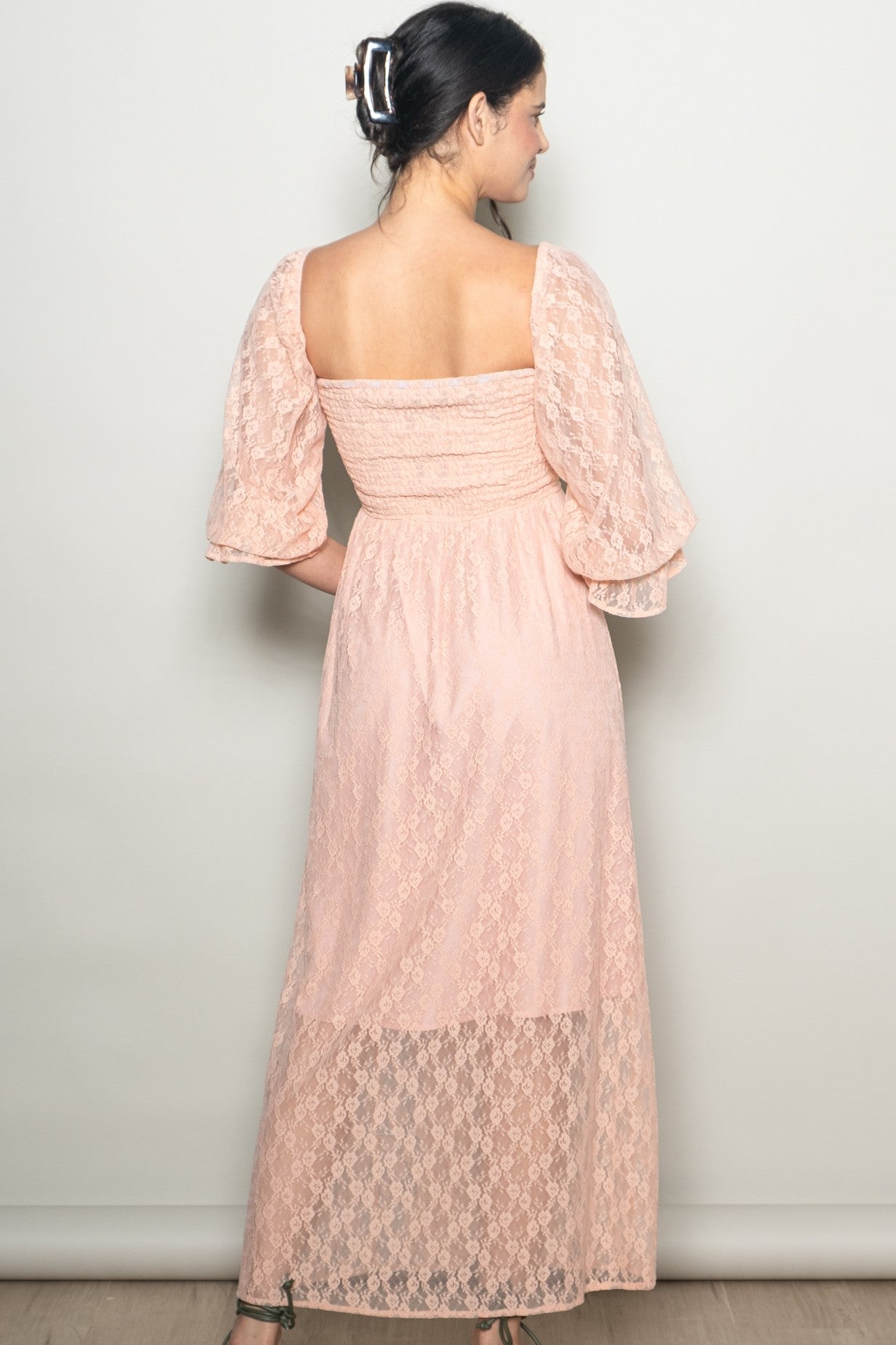 woman wearing a peach lace maxi dress with puff sleeves, showing the back view