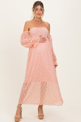 woman wearing a peach off-the-shoulder lace maternity dress and holding her baby bump