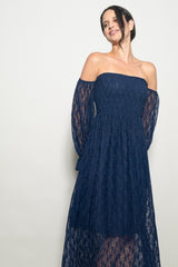 woman wearing a navy blue off-the-shoulder lace dress with long sheer sleeves and a fitted bodice