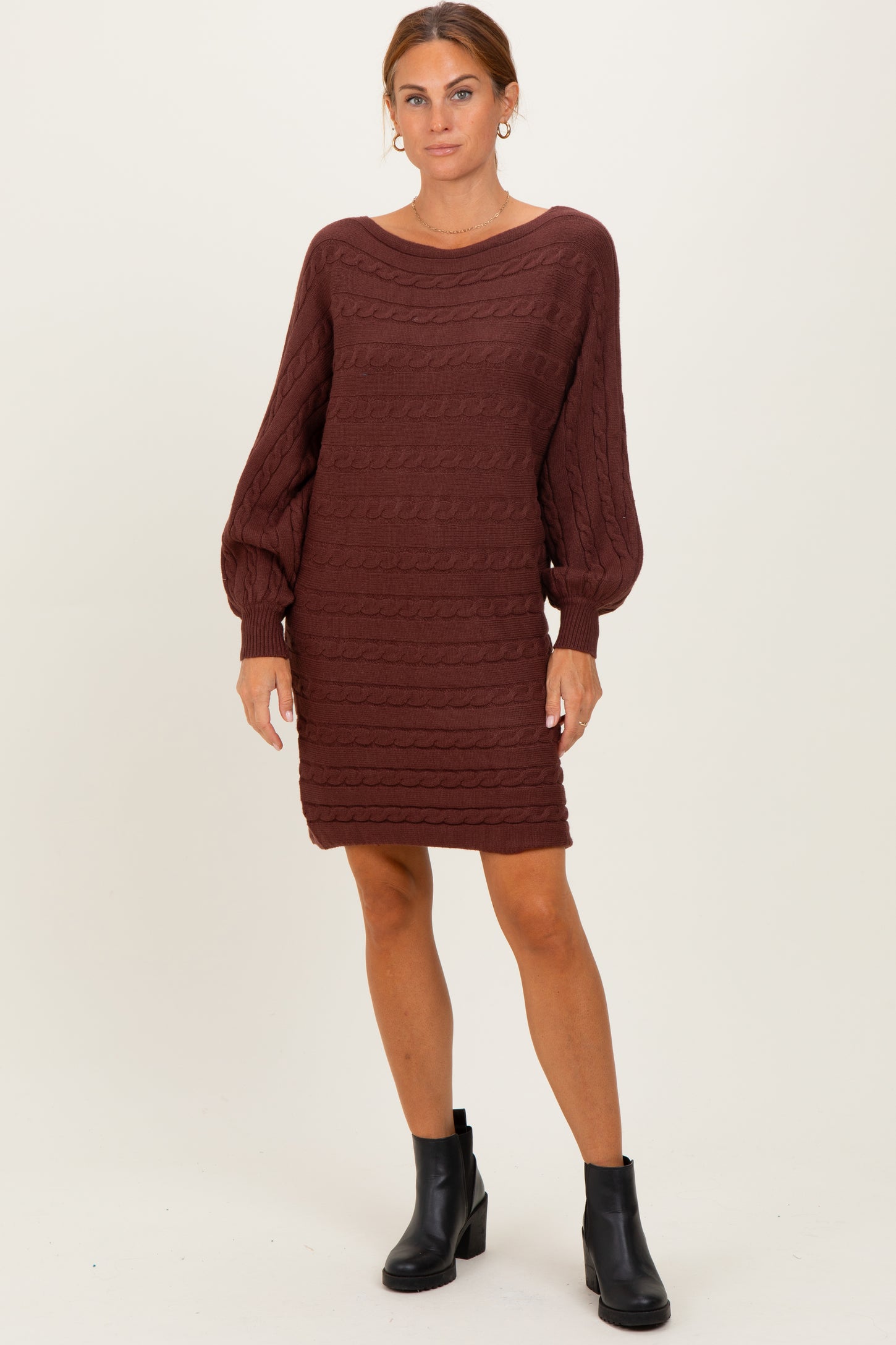 woman wearing a maroon cable knit sweater dress with balloon sleeves and black ankle boots