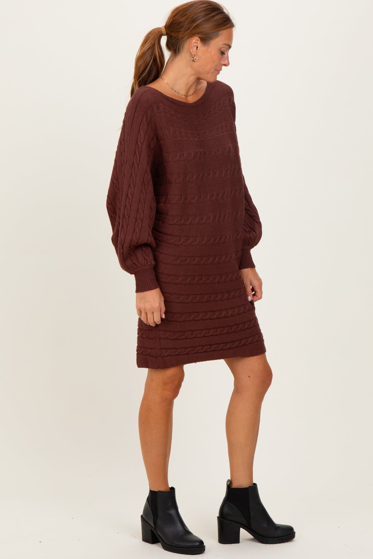 woman wearing a maroon cable knit sweater dress with long sleeves and a relaxed fit