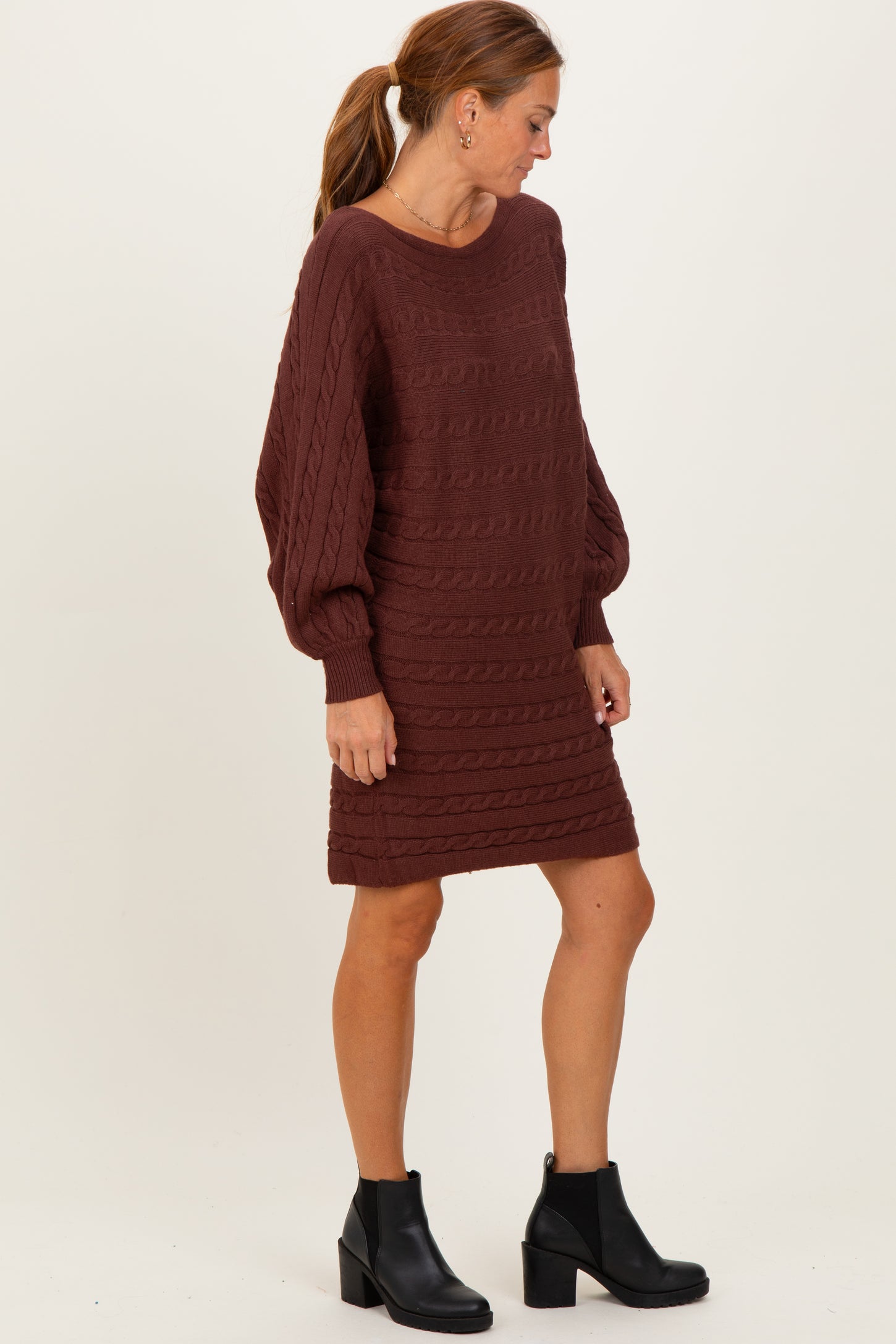 woman wearing a maroon cable knit sweater dress with long sleeves and a relaxed fit