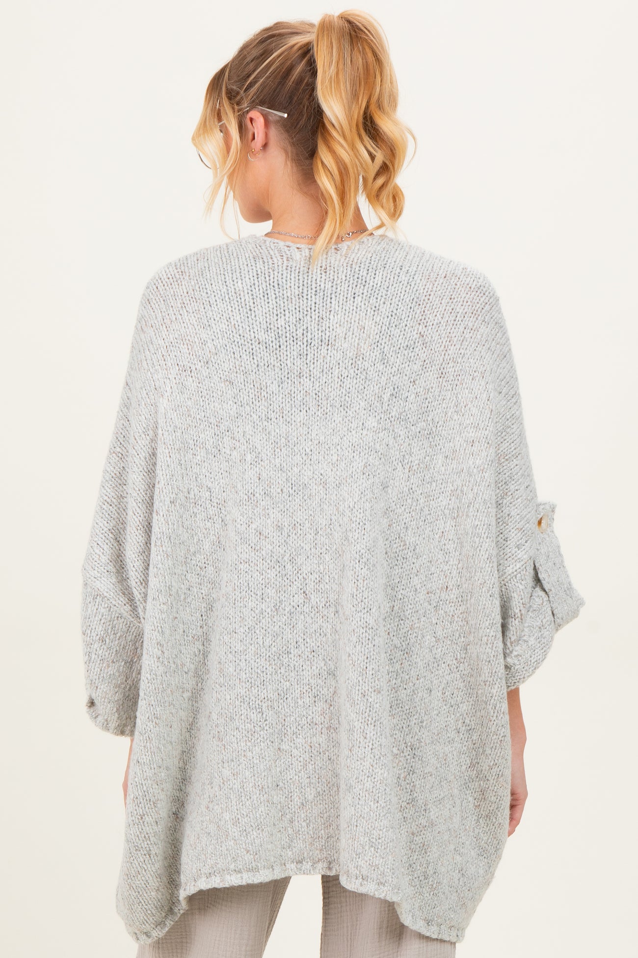woman wearing a light grey oversized maternity sweater with rolled sleeves, showing the back view