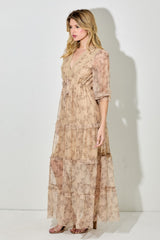 woman wearing a beige floral maxi dress with a tie waist and sheer tiered layers