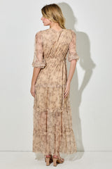 woman wearing a beige floral maxi dress with tiered ruffles and bell sleeves, viewed from the back