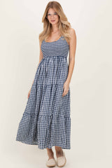 woman wearing a navy and white gingham maxi dress with tiered design and spaghetti straps
