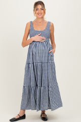 woman wearing a navy and white gingham maternity maxi dress, smiling and holding her baby bump
