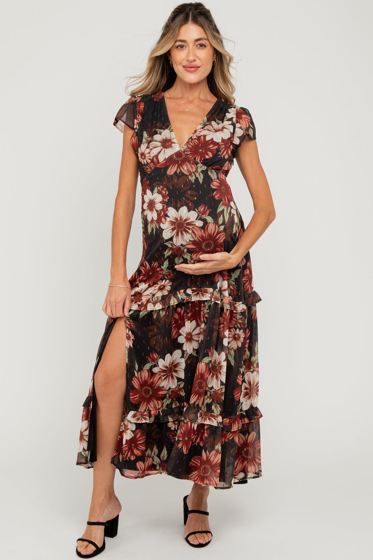 woman wearing a floral maternity maxi dress with ruffled tiers and a thigh-high slit, holding her baby bump