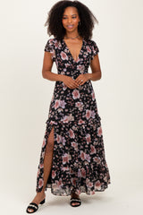 woman wearing a black floral maxi dress with ruffle details and a thigh-high slit
