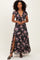 woman wearing a black floral maxi dress with ruffle details and a thigh-high slit