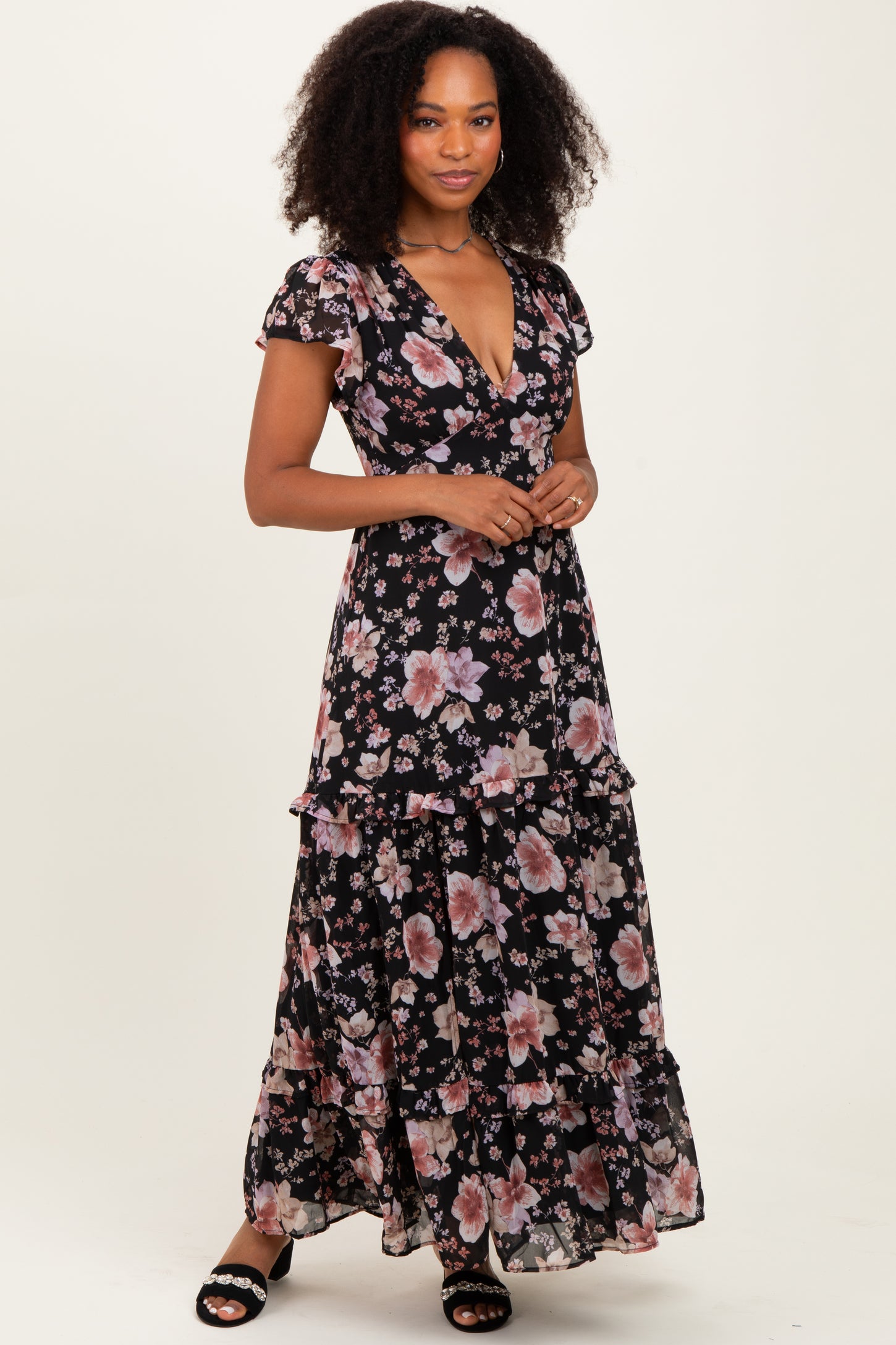woman wearing a black floral maxi dress with ruffled layers and short sleeves