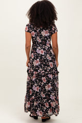 woman wearing a black floral maxi dress with short sleeves and ruffled hem, view from the back