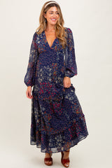 woman wearing a navy floral maternity maxi dress with long sleeves and a tiered skirt, showcasing her baby bump