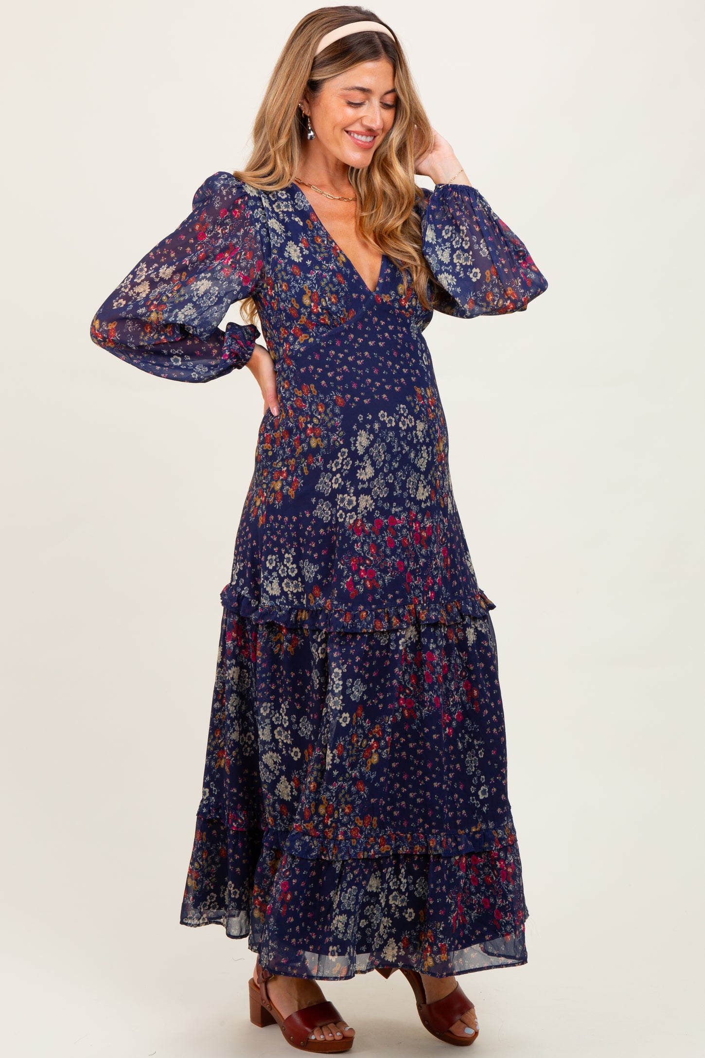 woman wearing a navy floral maternity maxi dress with long puff sleeves and a tiered skirt, showing her baby bump