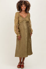 woman wearing an olive green maternity dress with long sheer sleeves and a ruched bodice, showcasing her baby bump