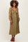 woman wearing an olive green maternity dress with long sheer sleeves and a ruched bodice, showcasing her baby bump