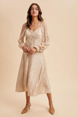 woman wearing a beige midi dress with lace long sleeves and a v-neckline, styled with subtle pleating at the bust