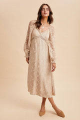 woman wearing a beige lace long sleeve dress with a v-neck and flowing silhouette, styled with beige flats