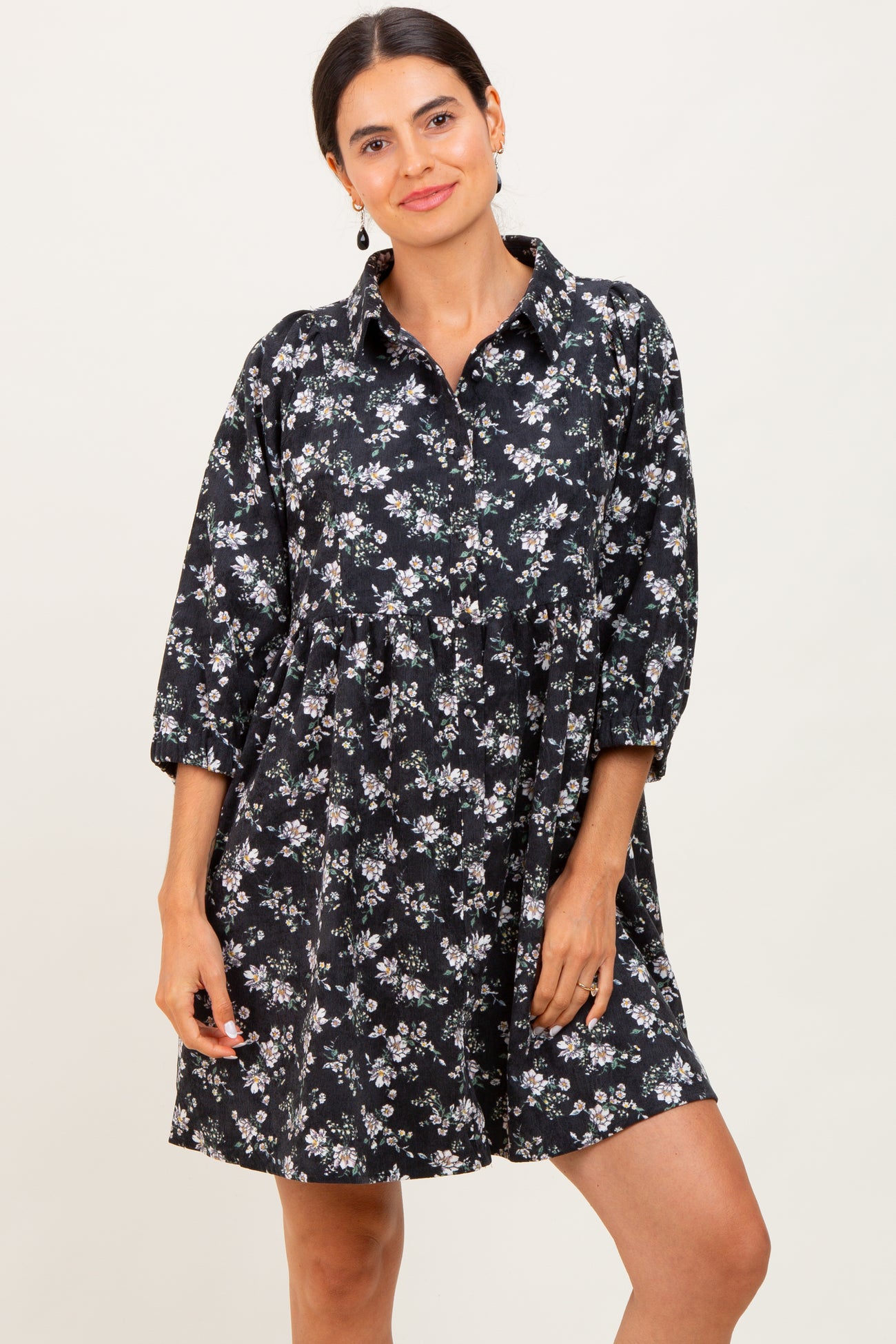 woman wearing a black floral button-up dress with three-quarter sleeves and a relaxed fit
