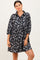 woman wearing a black floral button-up dress with three-quarter sleeves and a relaxed fit