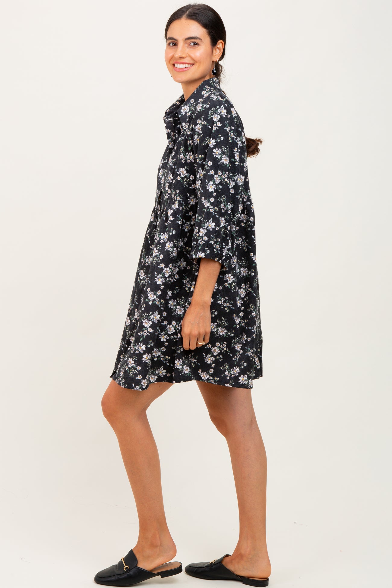 woman wearing a black floral shirt dress with three-quarter sleeves and black slide-on shoes