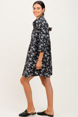 woman wearing a black floral shirt dress with three-quarter sleeves and black slide-on shoes