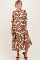 woman wearing a brown and white floral maxi maternity dress with short sleeves and a button-up front, showcasing her baby bump