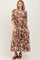 woman wearing a brown and white floral maxi dress with short sleeves and pockets