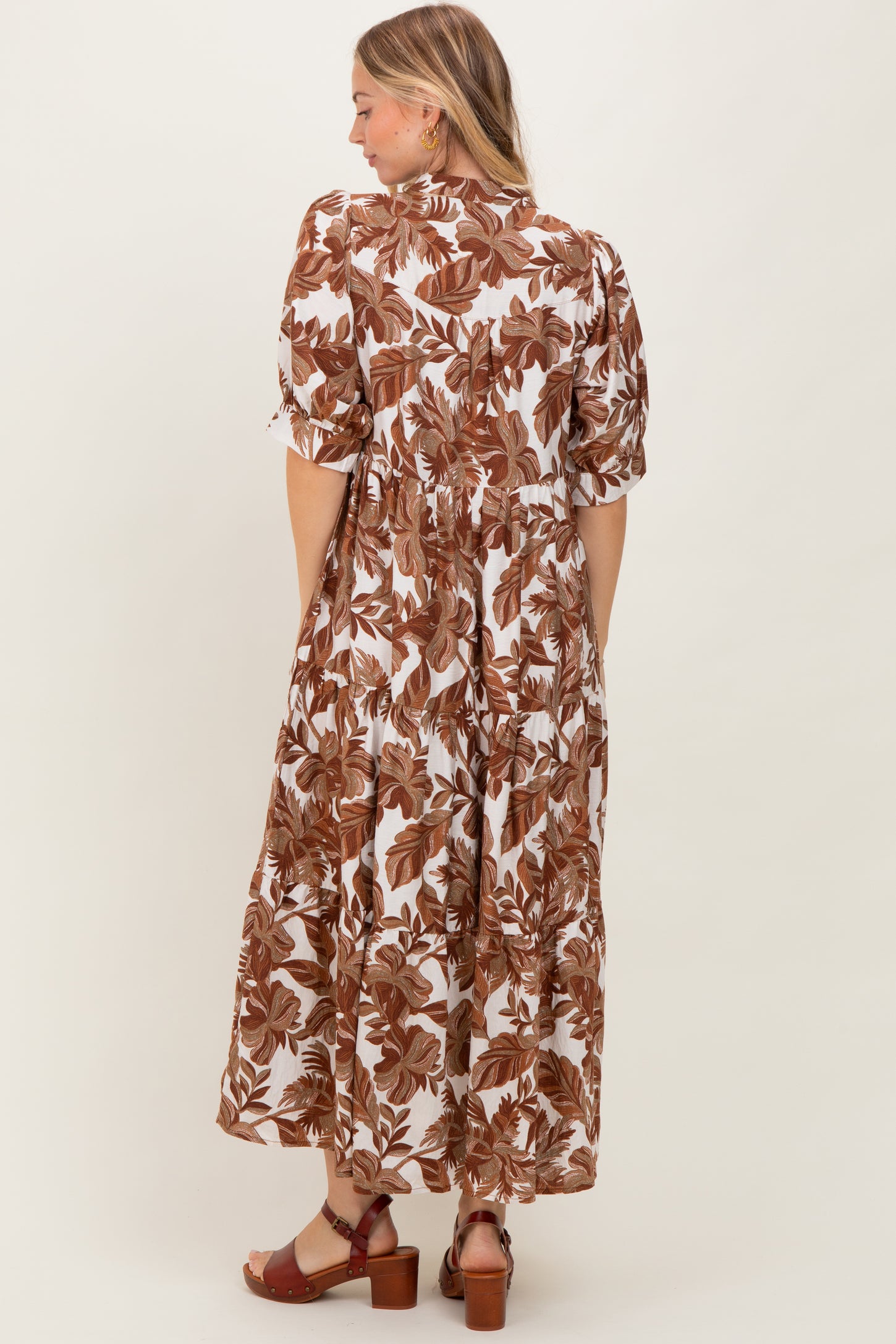 woman wearing a brown and white floral maxi dress with puff sleeves, showing the back view and a flowy silhouette