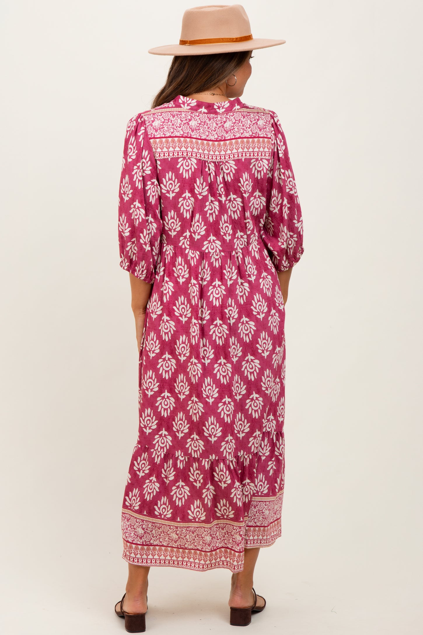 woman wearing a pink floral print maternity maxi dress with a flowy silhouette and puff sleeves