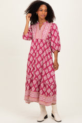 woman wearing a pink bohemian mid-length dress with floral patterns and a buttoned neckline