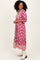 woman wearing a pink floral maxi dress with three-quarter sleeves and embroidery details, standing and smiling