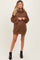 woman wearing a brown oversized cowl neck maternity sweater dress with bell sleeves and a visible baby bump